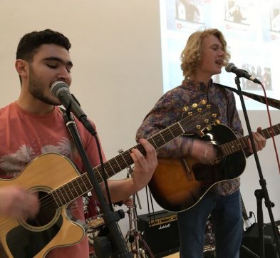 two teenage boys singing and playing guitar