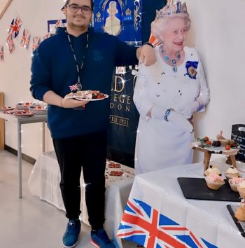 man standing with a cutout of the queen